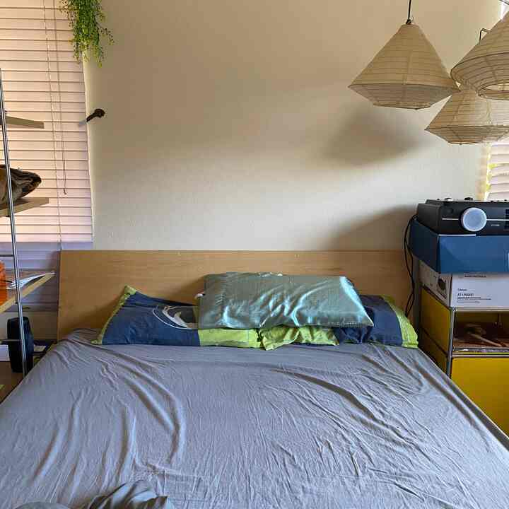 Natural tone bedroom featuring bed with blue and gray bedding, simple headboard and nightstand, Japandi style ambiance