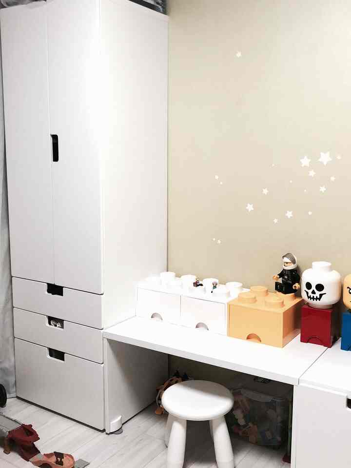 White-toned kids' room featuring white furniture and stool with LEGO toys and star stickers creating a cozy atmosphere