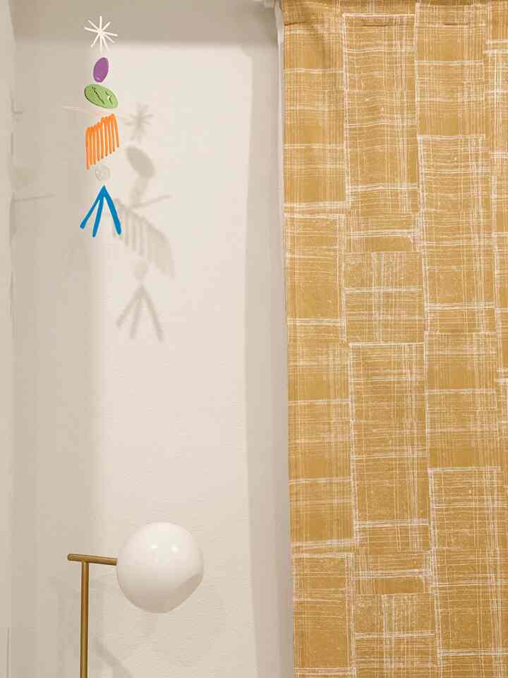 White-walled space with gold-toned curtains, featuring staggered glass pendant light, creating a minimalistic atmosphere