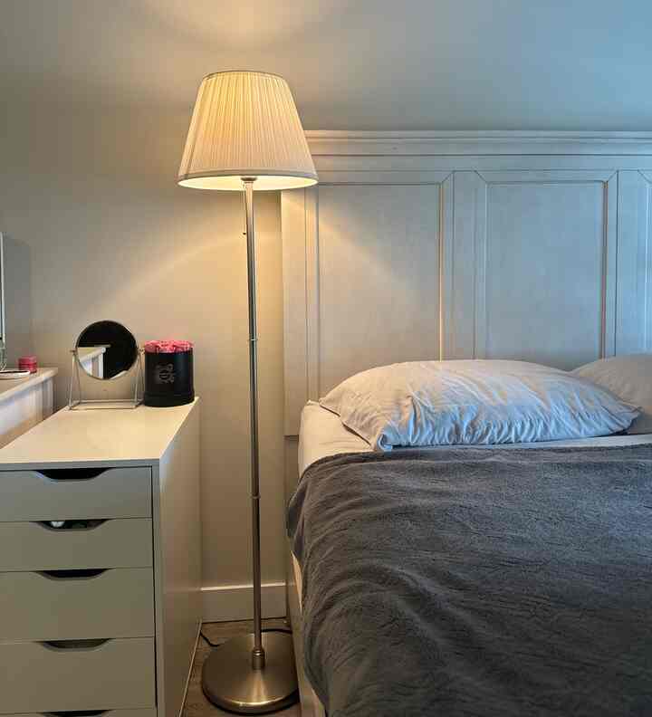 White and gray toned bedroom featuring bed, nightstand, and floor lamp in a simple and minimal setting