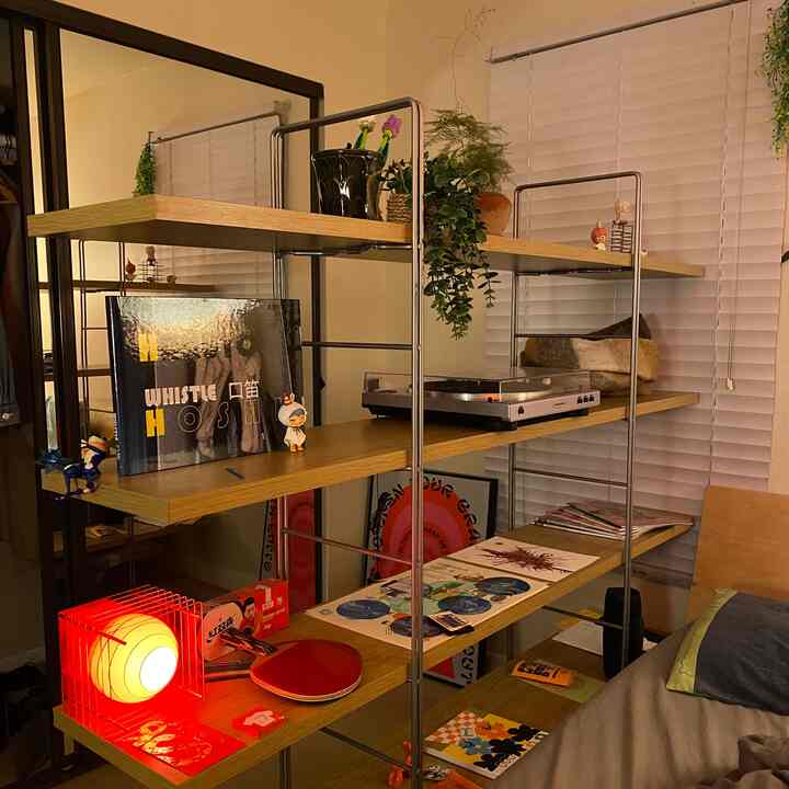 Cozy Japandi-style small room with wood tones and red lighting, featuring a bookshelf and turntable