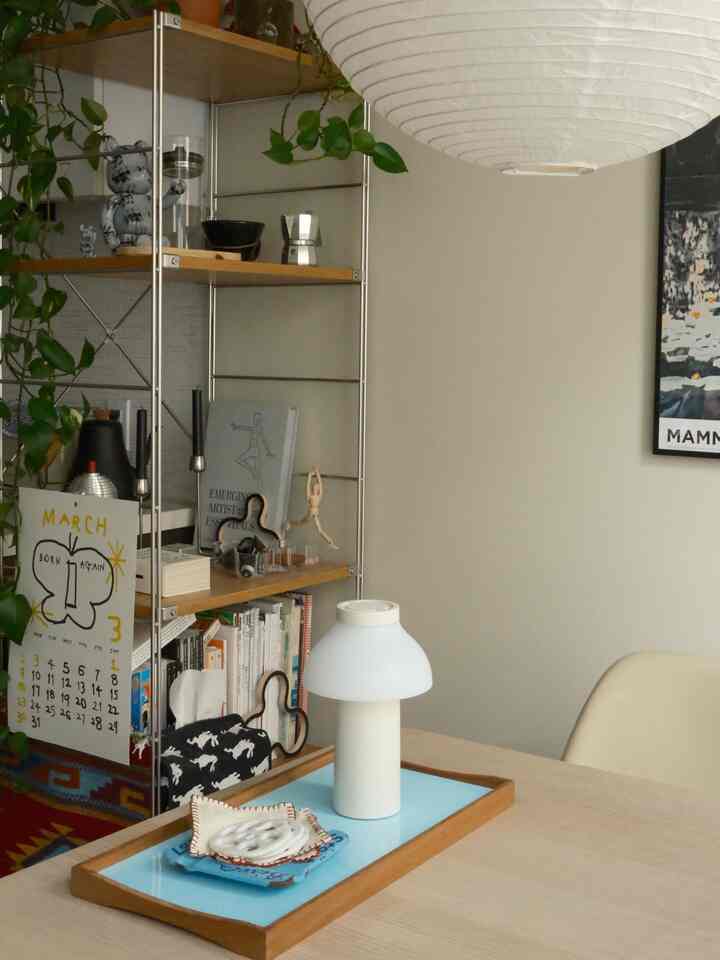 Beige-toned dining room with shelves, featuring a white table lamp and decor items on the table creating a cozy atmosphere