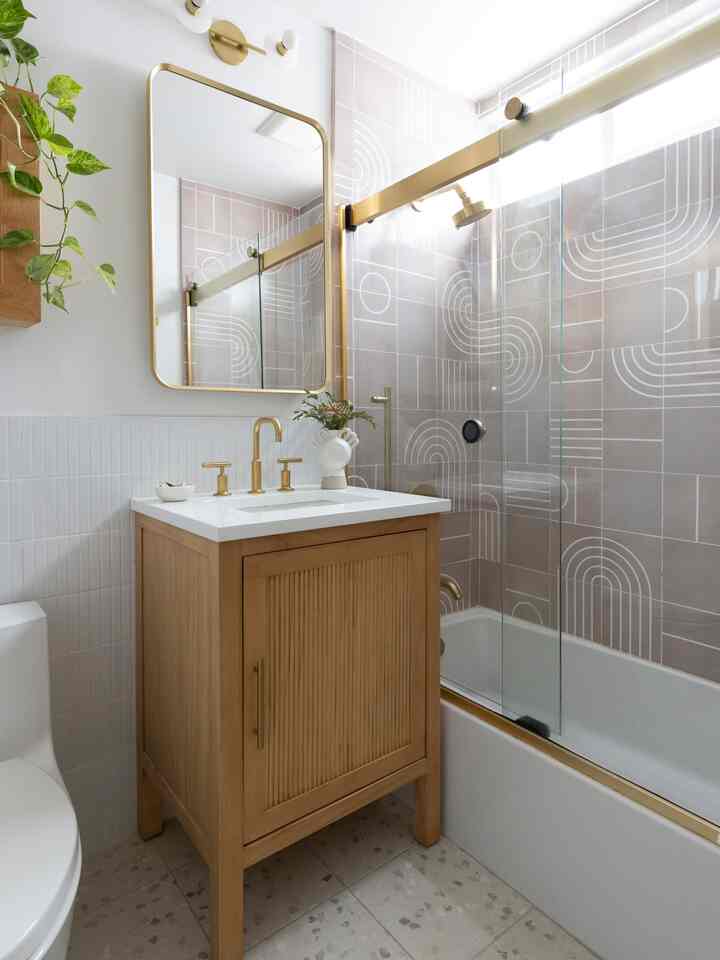 Natural beige toned bathroom with gold accents featuring a shower enclosure and wood vanity in a clean space
