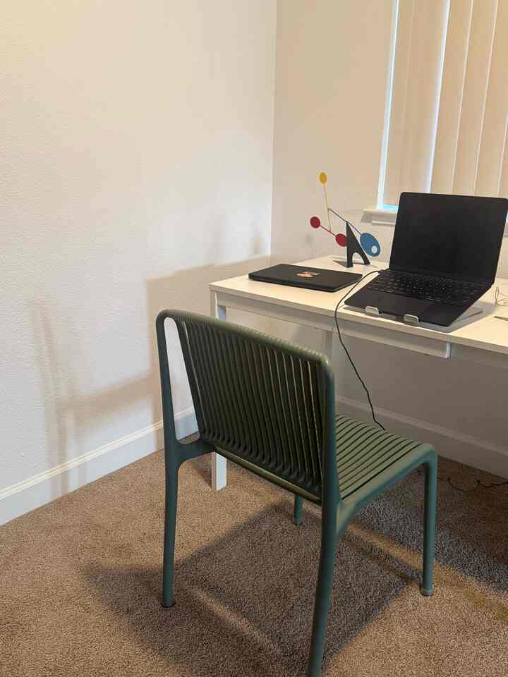 Simple white and beige toned home office featuring a white desk and green chair in a clean workspace