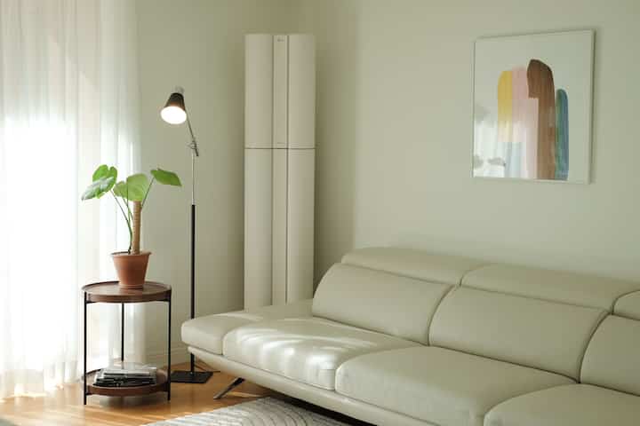 Bright natural-tone living room space featuring a cream leather sofa and a potted plant with a cozy atmosphere
