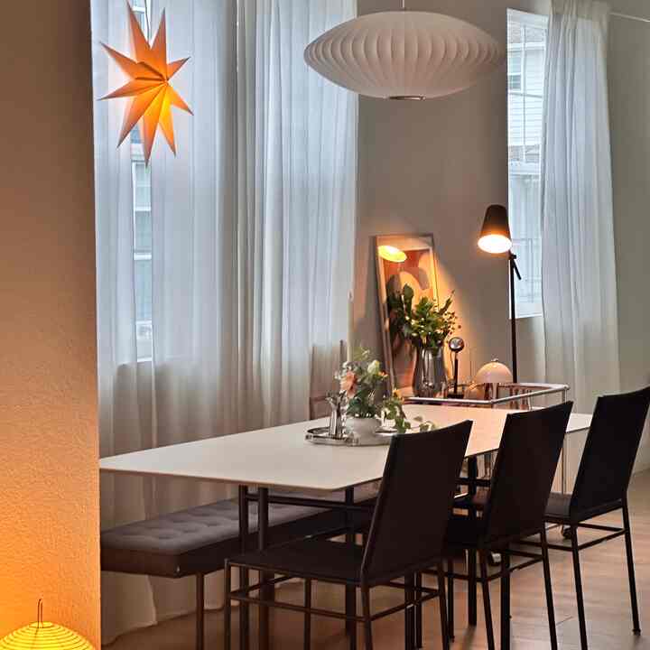 White and brown toned dining room featuring pendant light, dining table with chairs in a modern setting