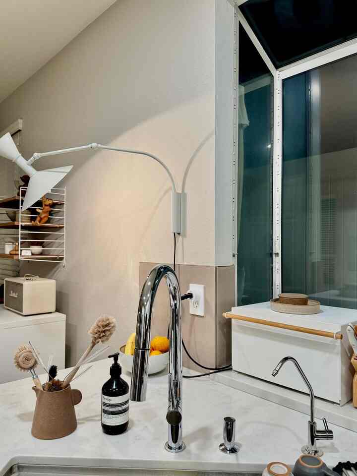 White and brown toned kitchen featuring chrome faucets and wall sconce in a clean organized space