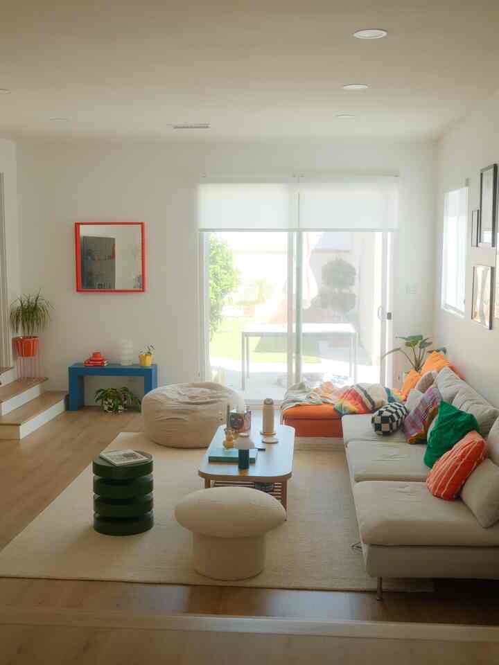 Cozy living room with white walls and ceiling, featuring an orange sofa and beige bean bag
