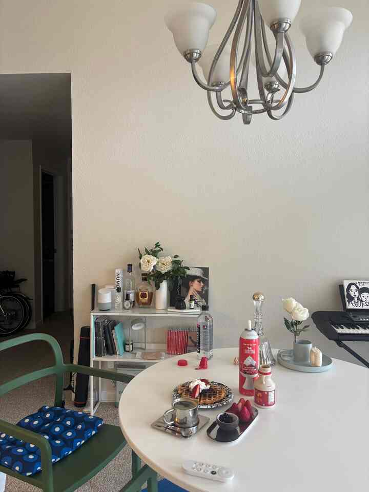 White walls and round dining table with green chairs create a cozy home cafe style living room space