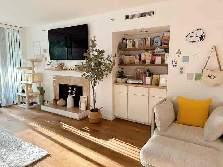 Cozy living room with warm wood tones and white walls, featuring a cat tower and a comfortable sofa armchair