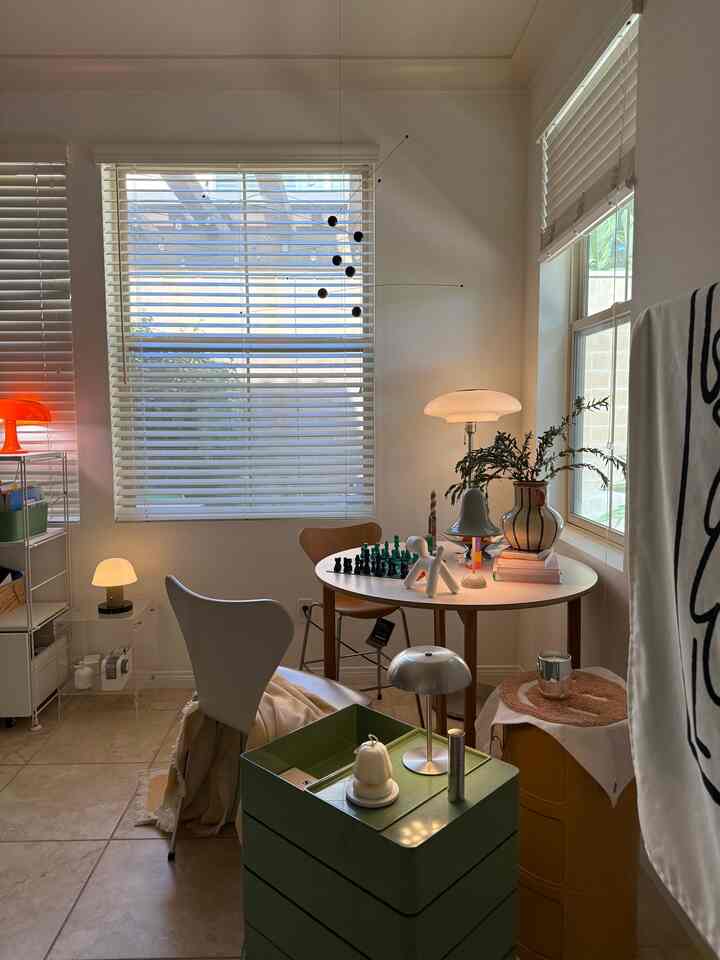 Bright white tone dining room featuring Mid-Century Modern chairs and round table, various table lamps and storage units creating a cozy space