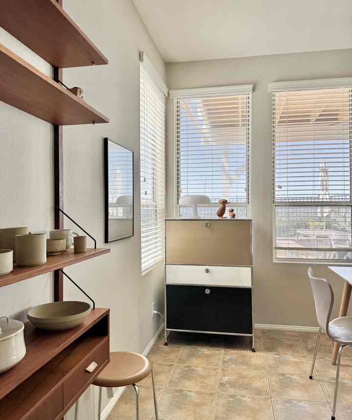 Beige walls and wood-toned shelves complement a bright dining room with sunlight streaming through windows