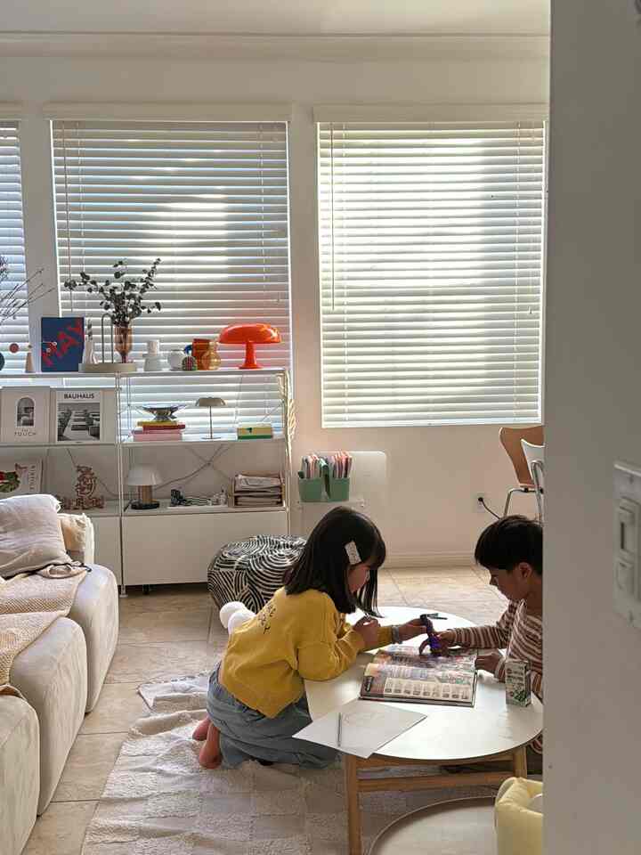 Natural and white-toned living room featuring bookshelf and side tables with a simple, kid-friendly atmosphere