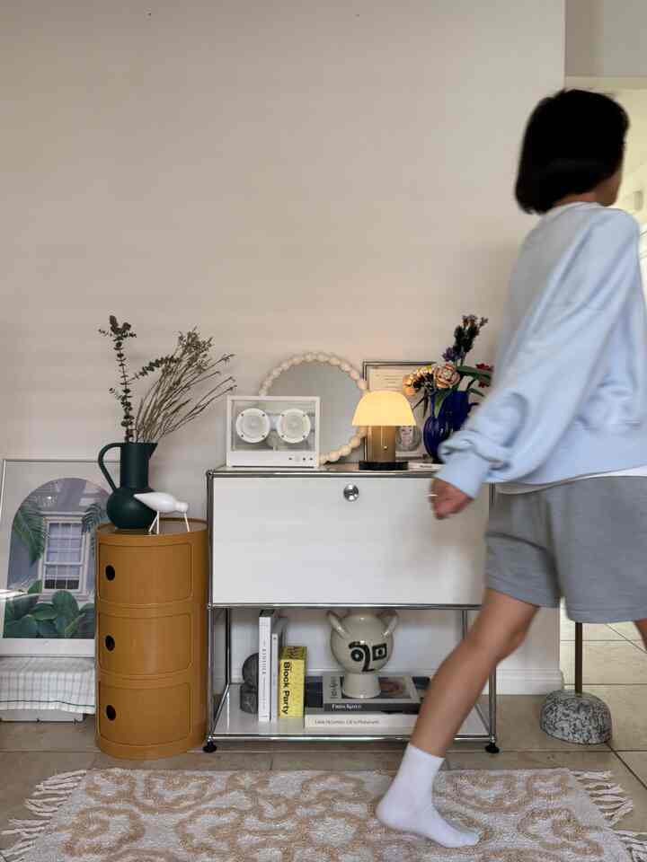 A white and warm-toned mid-century modern living room featuring a side table and table lamp creating a cozy atmosphere