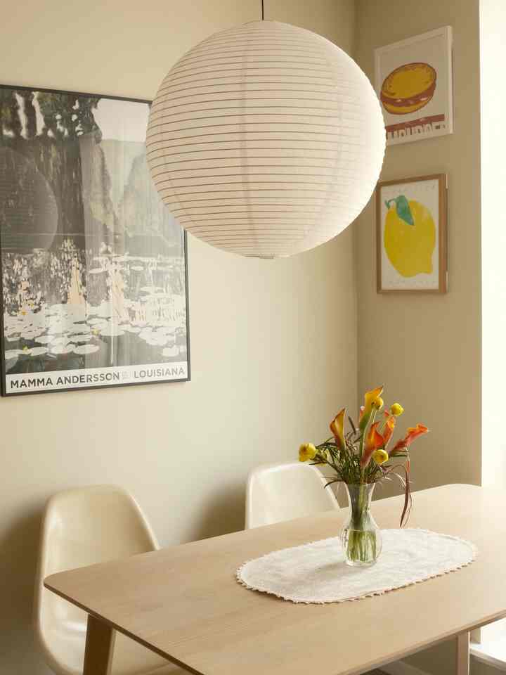 Beige walls and wood tone dining table with white spherical lamp in a two-person dining room space