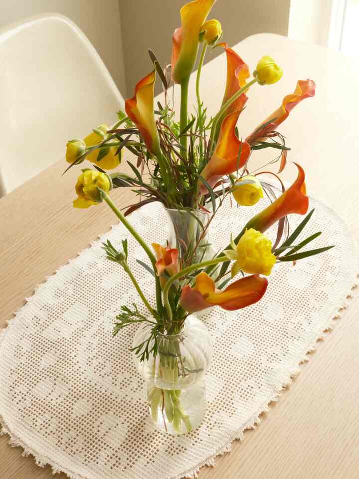 Warm natural color dining room featuring wooden table with glass vase and yellow-orange flowers beautifully arranged