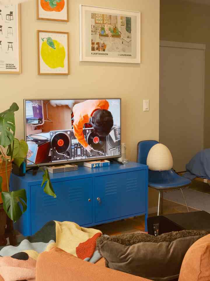 A warm modern living room featuring a blue storage cabinet and orange sofa with cozy accents