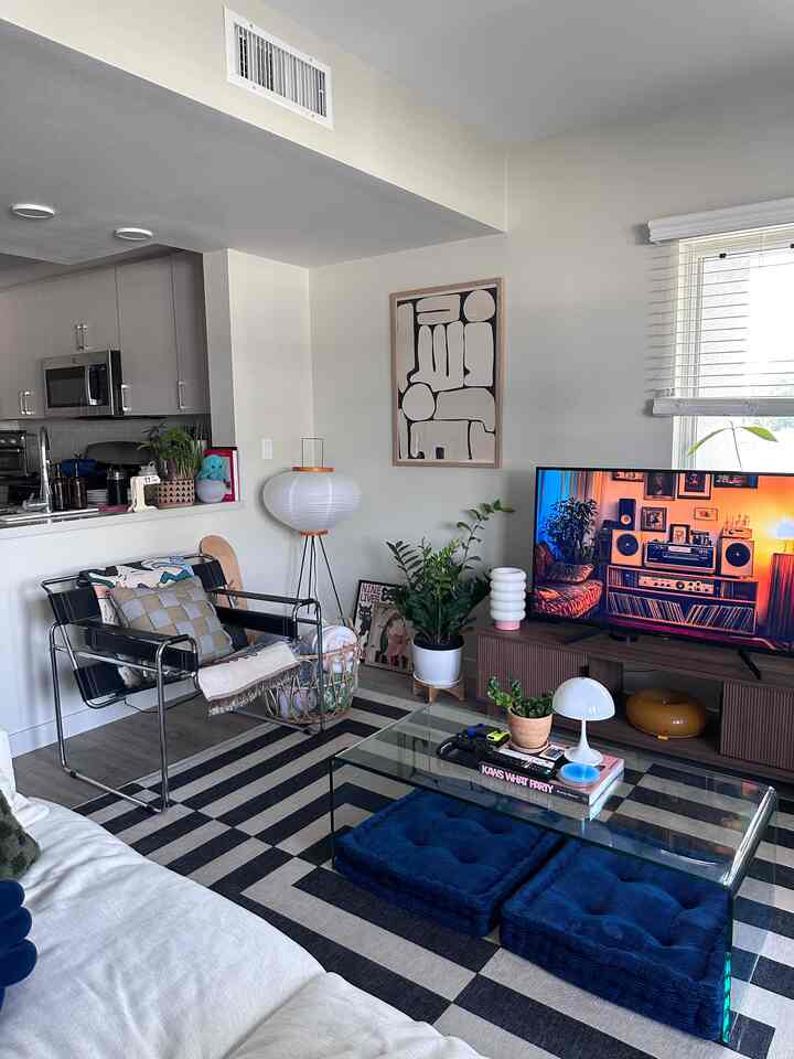 Natural modern tone living room featuring beige sofa, metal armchair, large geometric rug in cozy space