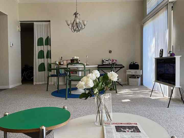 A living room in white and green tones featuring a central table and green chairs, creating a simple and natural atmosphere