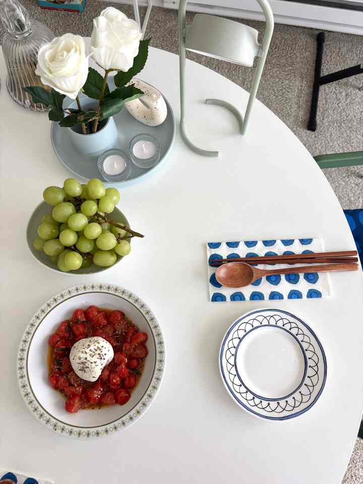 White table featuring plates with food and grapes, wood tone utensils, flowers and candles, creating a natural color cafe style home cafe setup