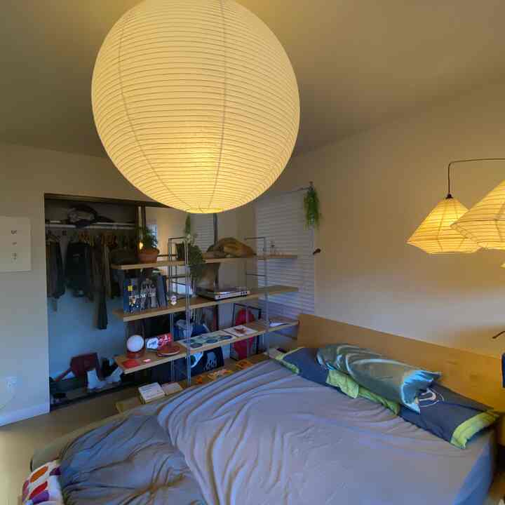 Natural-toned bedroom featuring wooden bed frame and paper pendant lighting with a warm and cozy atmosphere