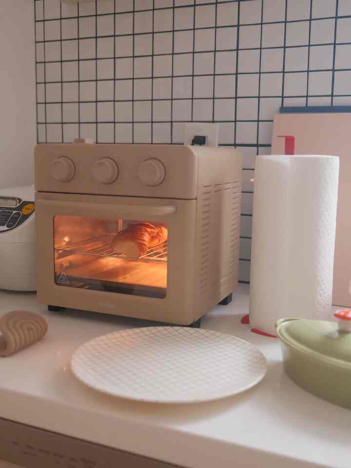 Beige and white toned kitchen featuring a beige Our Place Wonder Oven and kitchen items on a clean countertop with cozy ambiance