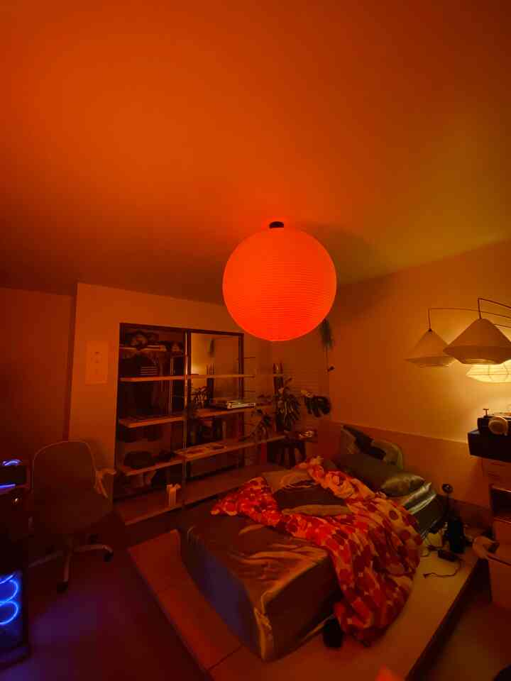 Cozy bedroom with warm orange mood light, featuring a bed and bookshelf in a natural color scheme