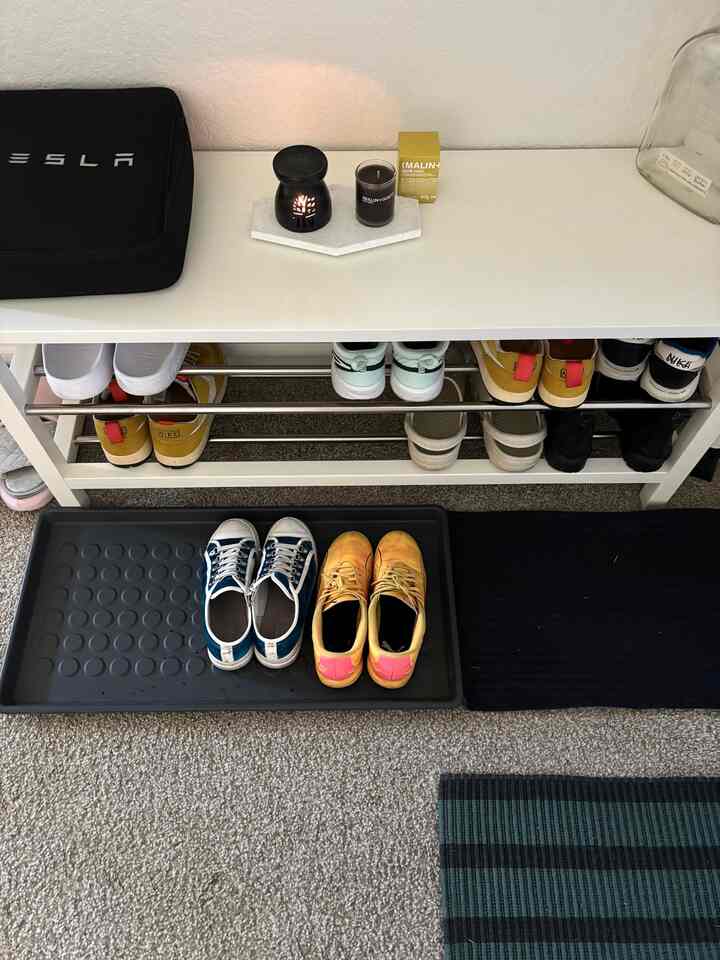 White and black-toned entrance area featuring a bench and shoe storage rack creating a clean and functional atmosphere