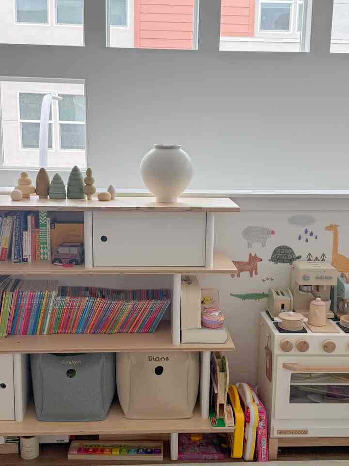 Natural-toned kids' room with white and beige hues, featuring a bookshelf and organized children's toys