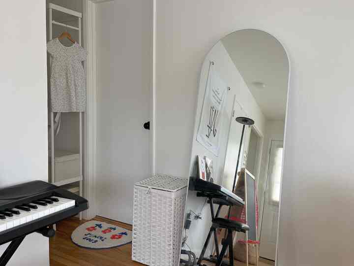 A white 6-tatami room featuring a full-length mirror and wicker laundry hamper, creating a simple space