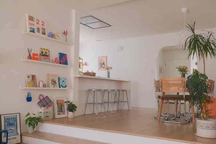 Natural color and wood tone dining room featuring dining table, chairs, plants, and shelves with a cozy atmosphere
