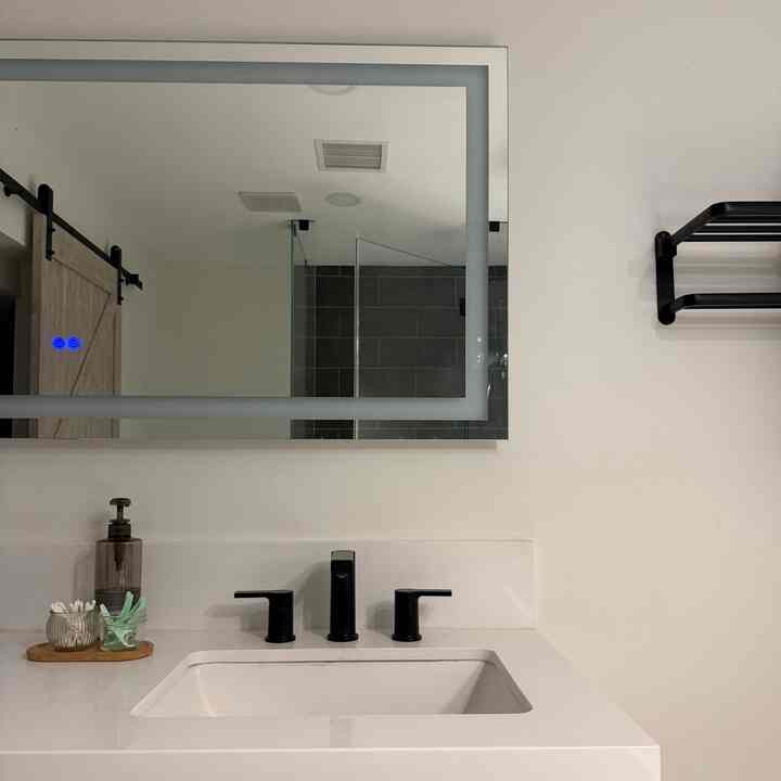 Monotone minimal bathroom with white walls, black faucets, washbasin, and LED-lit mirror