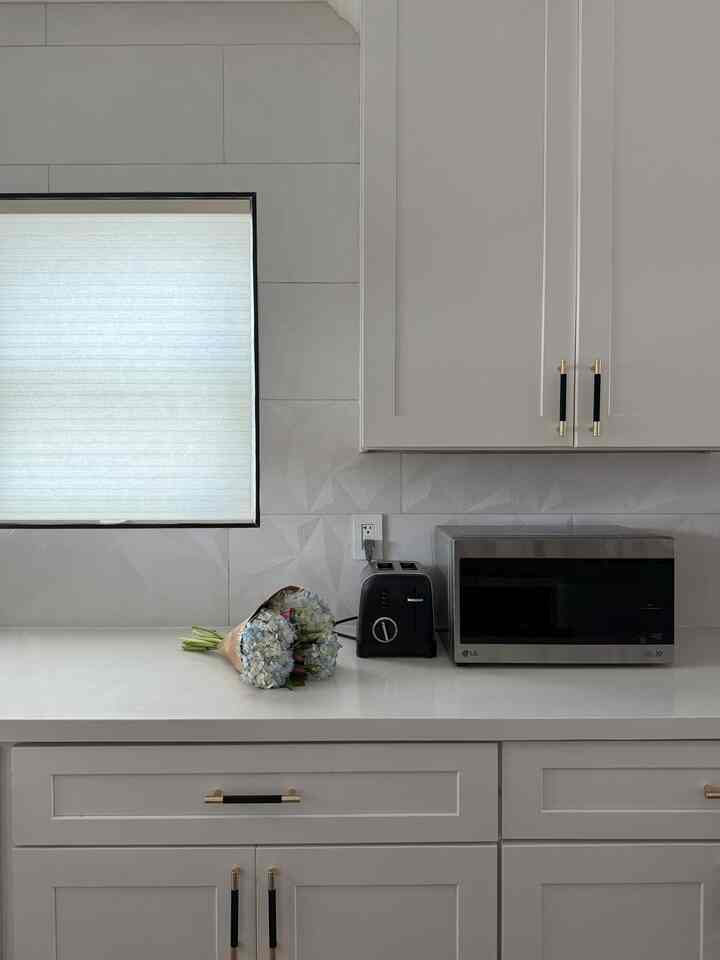 Minimal white and black kitchen counter featuring a bouquet of flowers and appliances on a clean surface