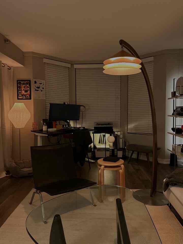 Beige and wood-tone living room featuring modern desk, lighting, and lounge chair in a cozy home office setup