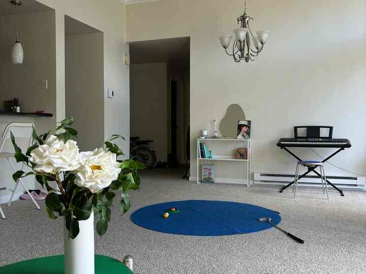 White toned living room with blue rug and digital piano arranged in a compact space