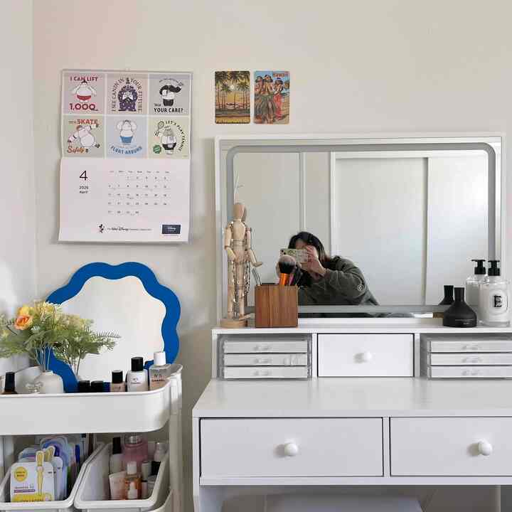 Simple vanity area with white and blue tones featuring a large mirror and compact storage, suitable for a single household