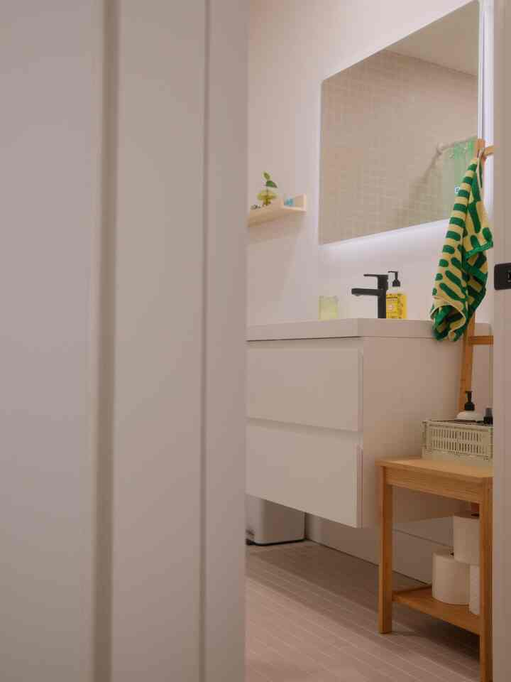 Soft white and wood tone bathroom featuring a washbasin, mirror, and towel arranged in a clean and cozy interior