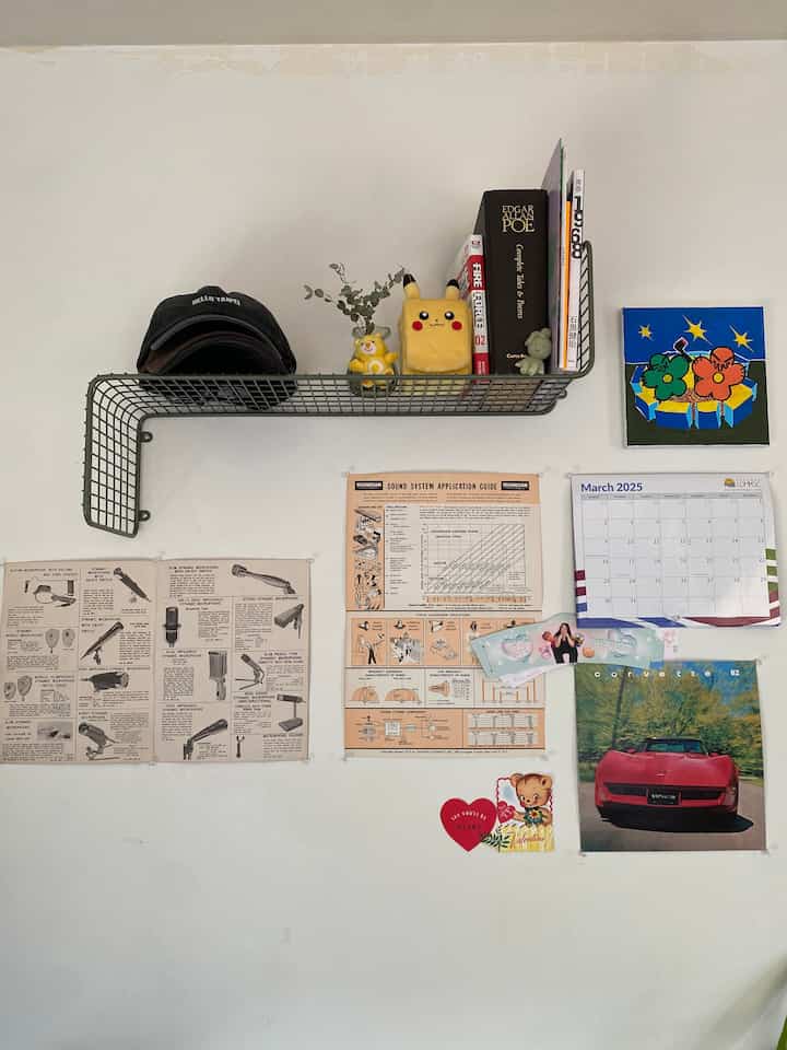 Bright white wall with a metal shelf displaying various knickknacks and books in a tidy home office setting