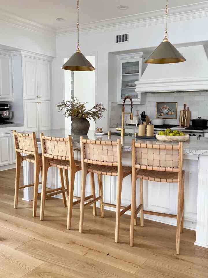 Natural color and white toned kitchen featuring wooden stools and a clean, modern kitchen island setup