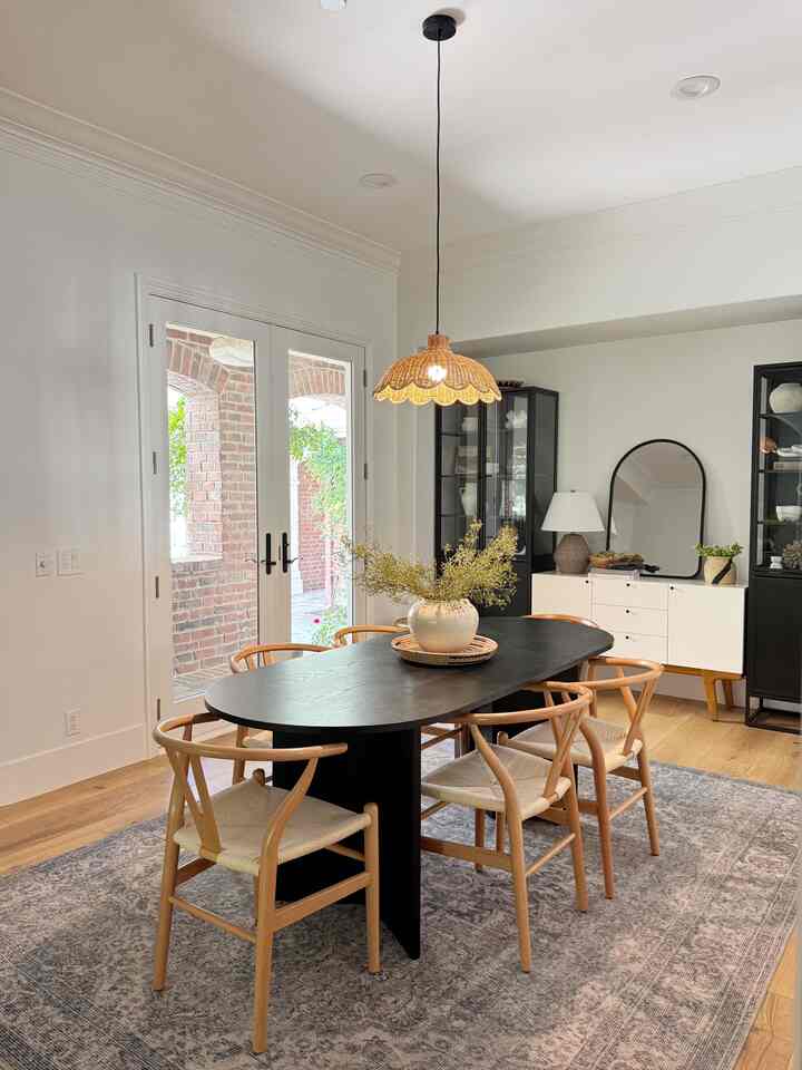 Modern dining room with natural wood tones and black furniture, featuring pendant light and dining chairs in a cozy setting