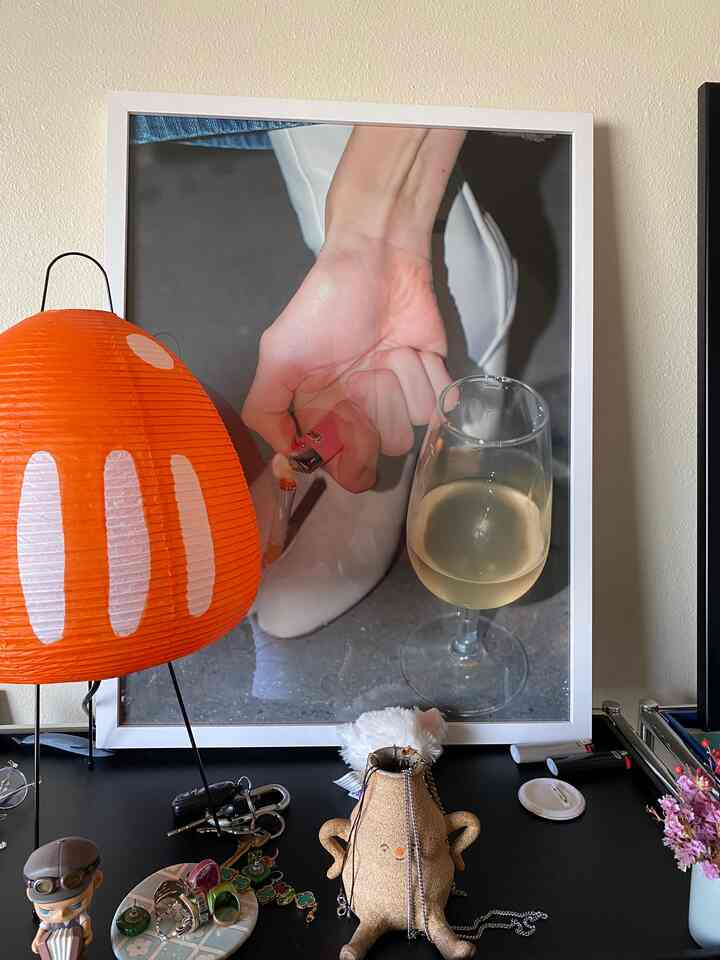 Cozy small space featuring an orange paper lamp, assorted trinkets on a black table, and a white framed photo in background
