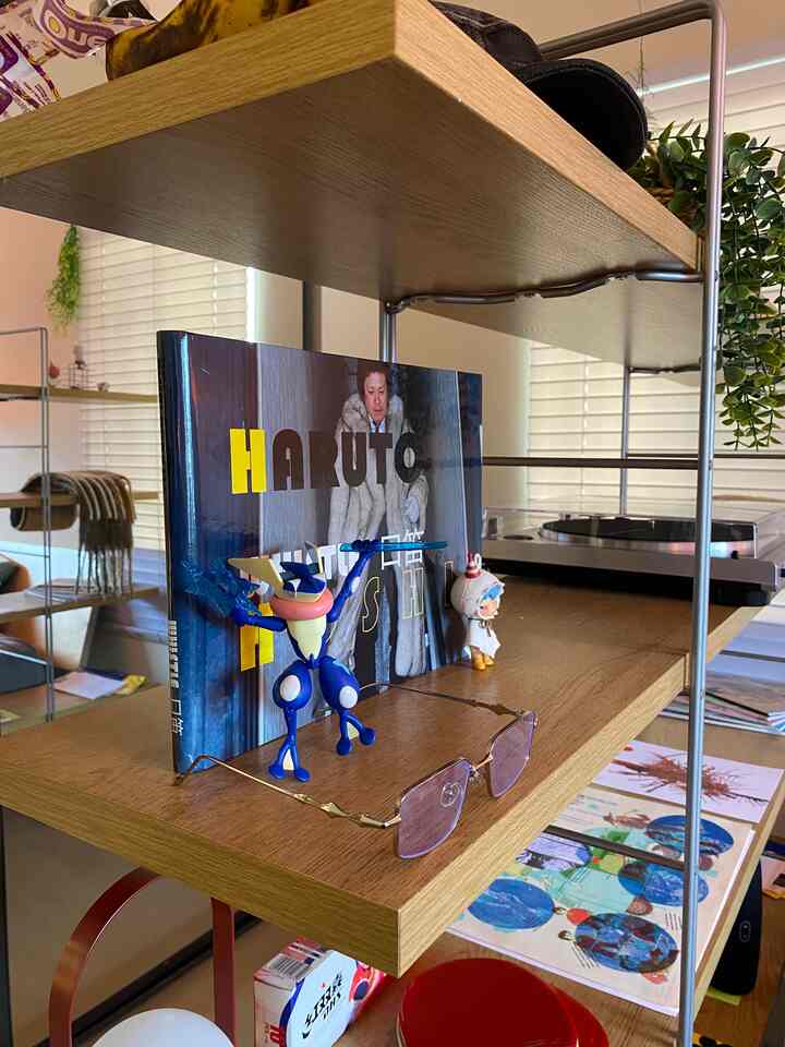 Natural tone wooden shelves featuring a blue figurine and turntable in a simple, organized Japandi-style space