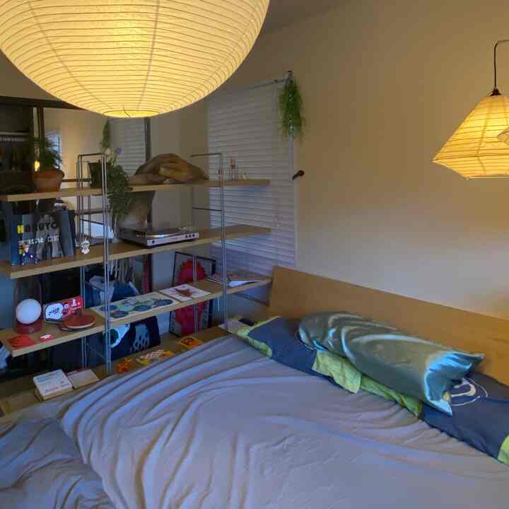 Natural wood-tone bedroom featuring a wooden bed frame, open storage shelves, and soft ambient paper lantern lighting for a cozy atmosphere