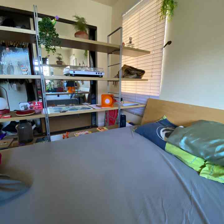White and wood tone bedroom featuring single bed and metal shelving with Japandi minimalist style in a compact space
