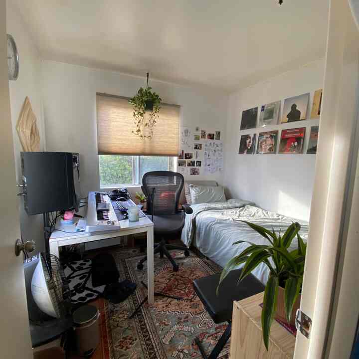 Beige and white toned compact bedroom with computer desk, office chair, and patterned carpet in a minimal Japandi style