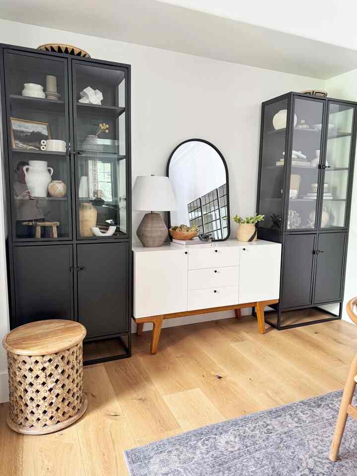 Modern and clean dining room featuring black metal-frame cabinets and a white mid-century modern storage sideboard