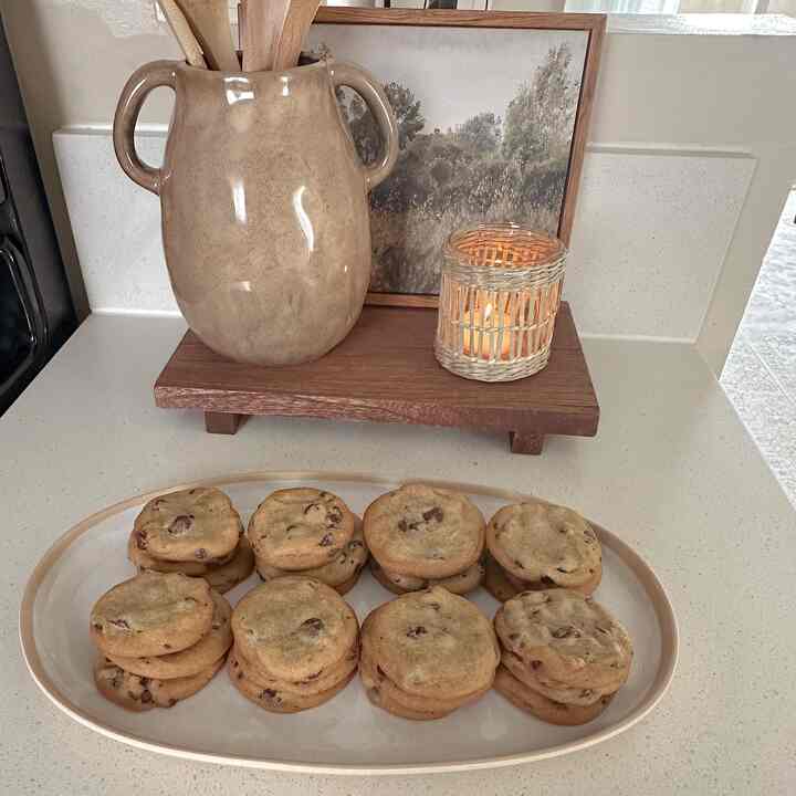 Brown-toned kitchen featuring a large ceramic vase, a lit candle, and cookies arranged on a plate creating a warm atmosphere