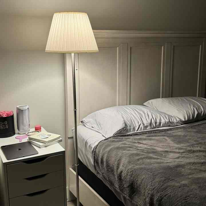 Gray and white toned bedroom featuring bed, nightstand, and floor lamp creating a cozy atmosphere