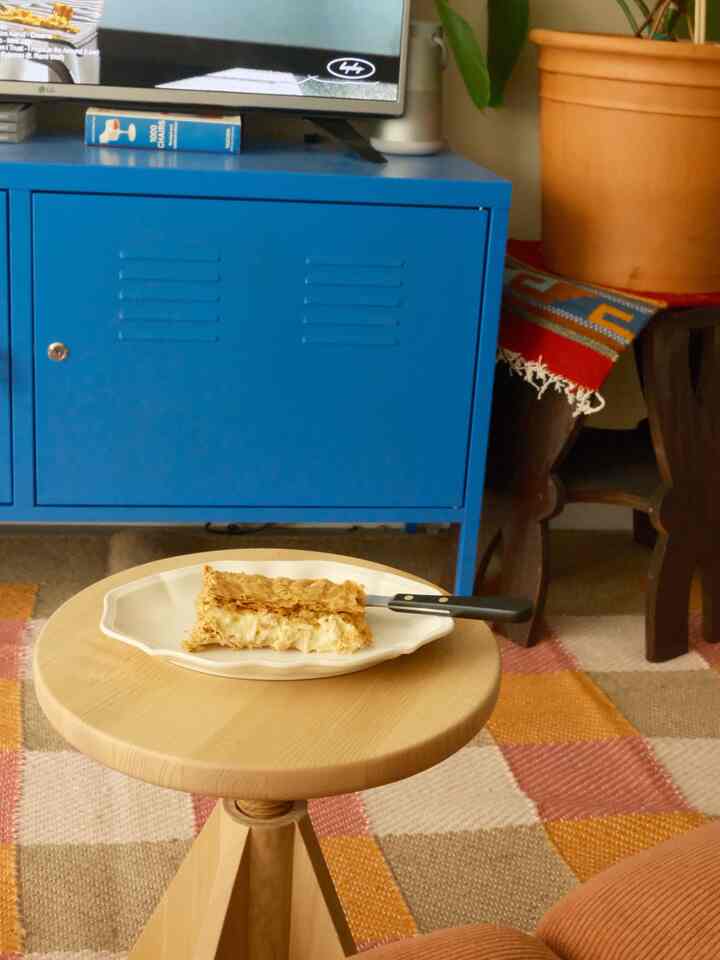 Natural wood tones and bright blue blend in a living room, featuring a wooden stool and vibrant rug creating a cozy atmosphere