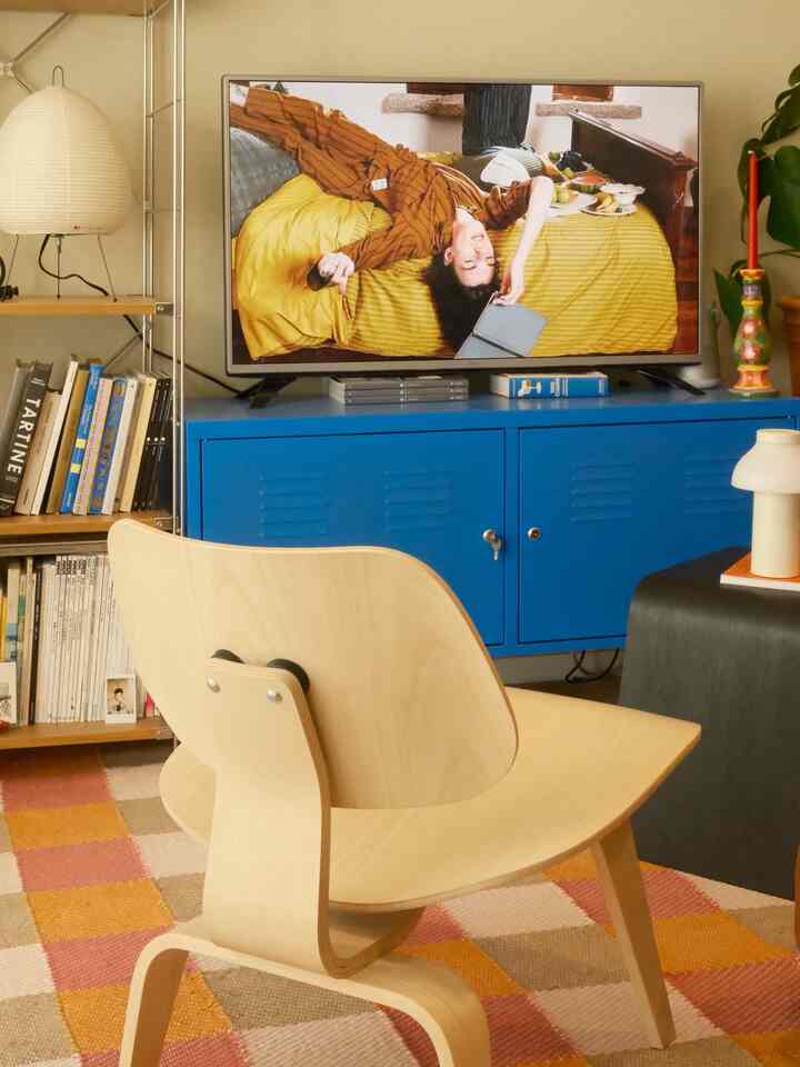 Natural-tone living room featuring a blue TV stand and wooden armchair with cozy atmosphere